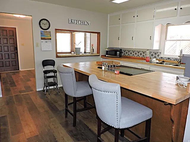 Kitchen featuring a built-in cooktop, light wood-finish countertops, and white cabinetry