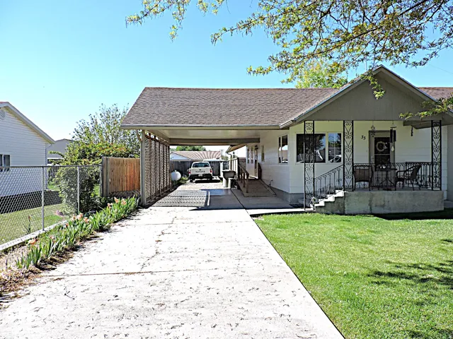 Single-story residence featuring a covered front porch with decorative ironwork, an attached carport, and a concrete driveway