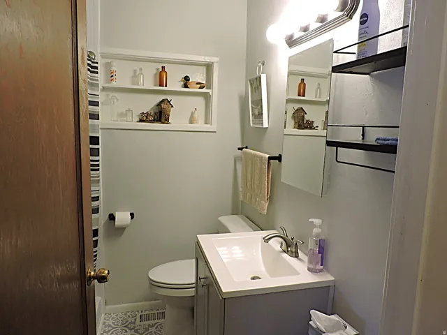 Bathroom featuring a vanity with an integrated sink, built-in recessed shelving, patterned floor, and a light fixture with multiple bulbs