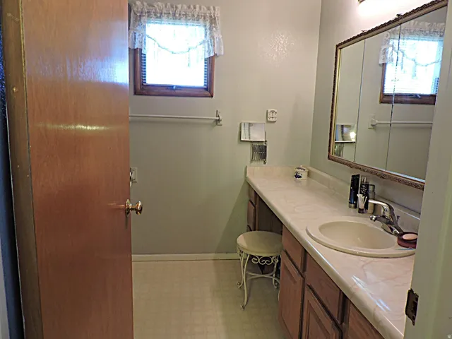 Bathroom featuring an extended vanity with an integrated sink, wood-finish cabinetry, and a mirrored medicine cabinet