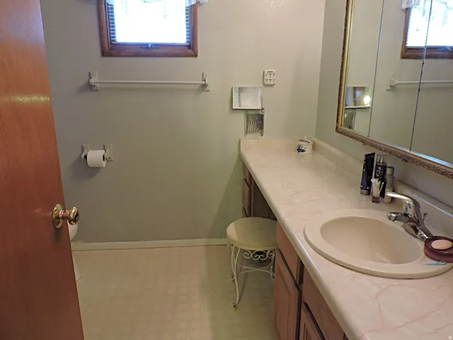 Bathroom featuring an extended vanity with an integrated sink, wood-finish cabinetry, and a mirrored medicine cabinet