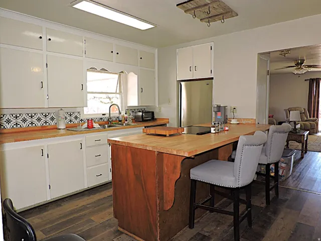 Kitchen with wood-finish flooring, white cabinetry, and a patterned tile backsplash