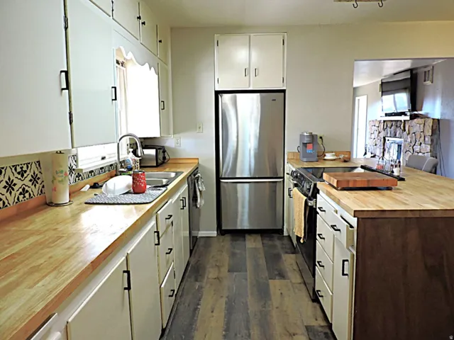 Kitchen featuring white cabinetry with black hardware, wood-finish countertops, and a patterned backsplash