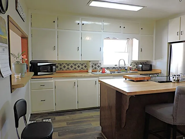 Kitchen featuring white cabinetry, wood-finish countertops, and a patterned tile backsplash