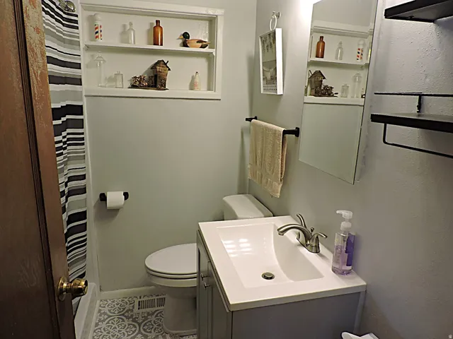 Bathroom featuring a white vanity with an integrated sink, brushed nickel faucet, and patterned floor tile