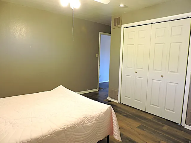 Room featuring wood-finish flooring, neutral wall paint, and a white bi-fold closet