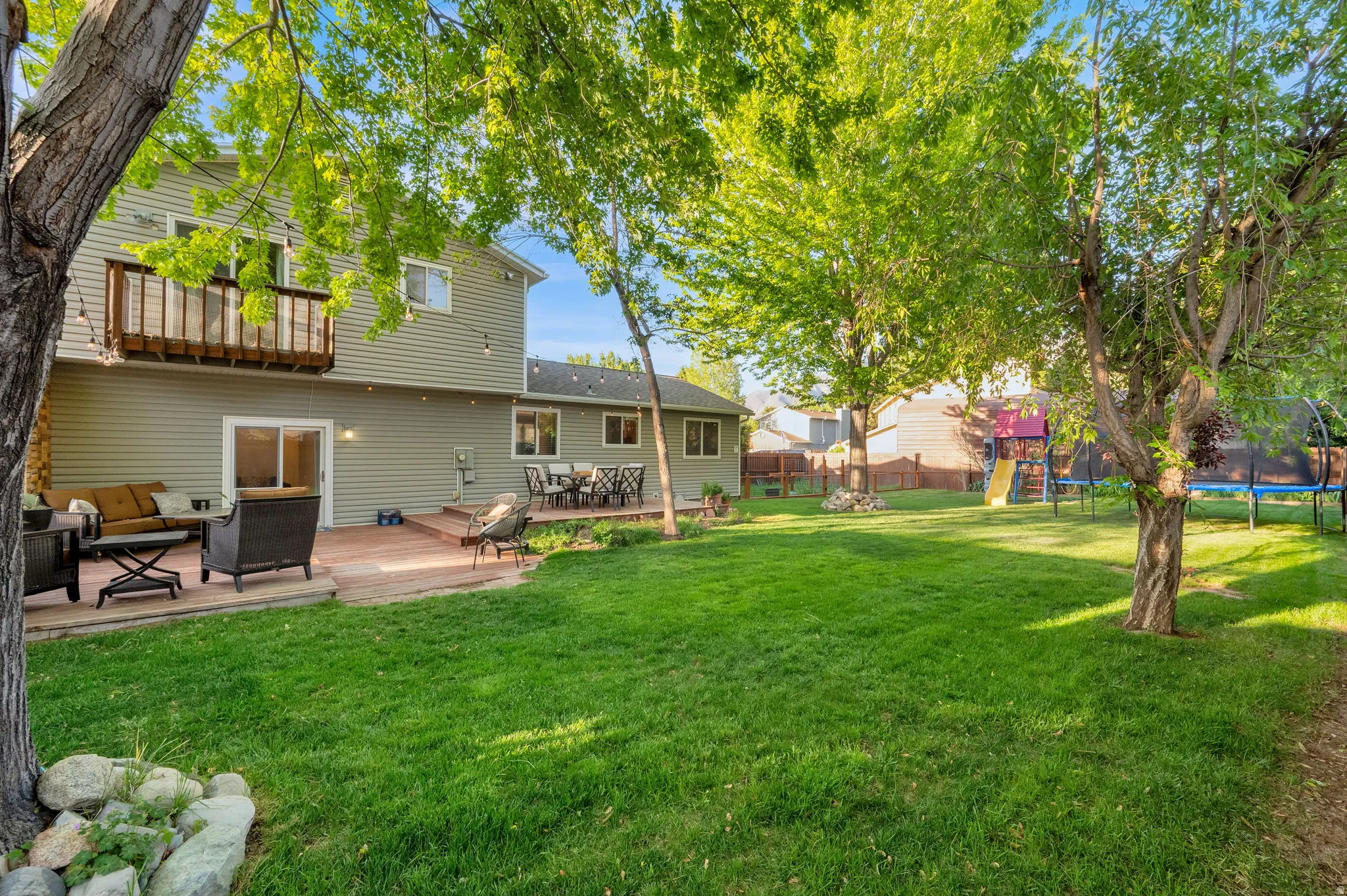 Expansive backyard featuring a lush lawn, mature trees, and a multi-level deck system