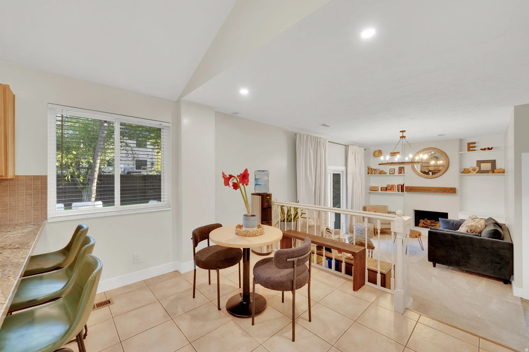 Open-concept living space with tile flooring, recessed lighting, and a kitchen pass-through featuring a tiled backsplash