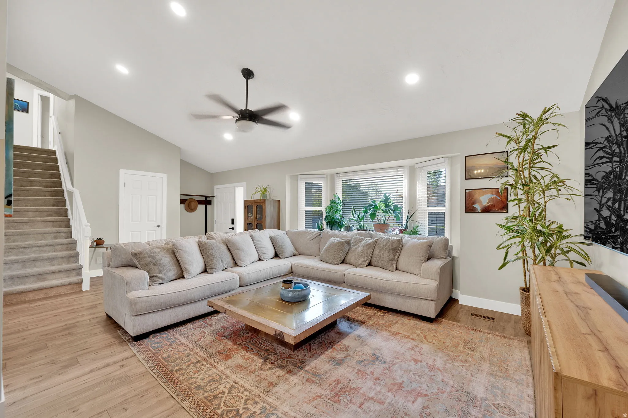 Spacious living area featuring vaulted ceilings, recessed lighting, and wood-finish flooring