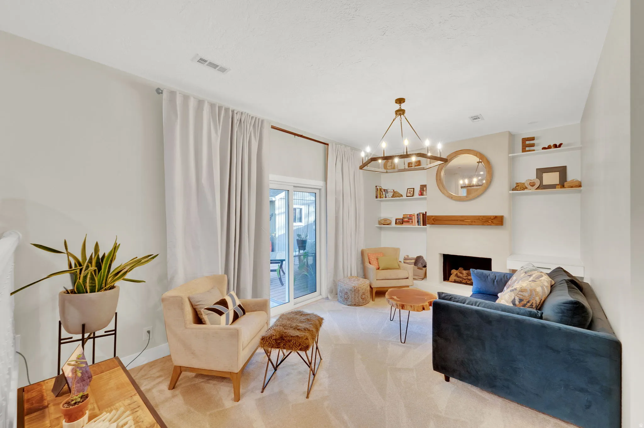 Living area featuring a central fireplace with wood mantle, built-in shelving, and a modern chandelier