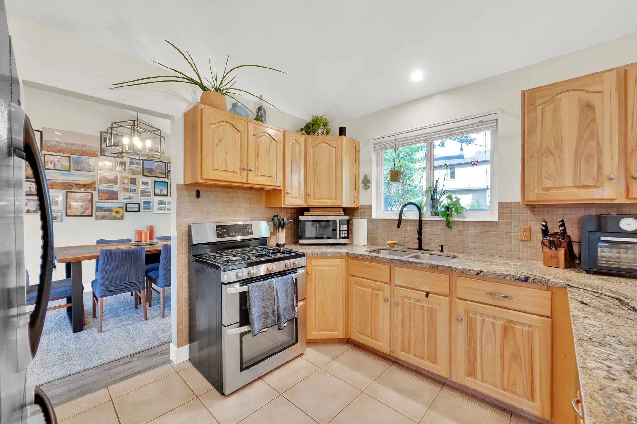 Kitchen featuring natural wood cabinetry, stone-finish countertops, stainless steel appliances, and tile flooring