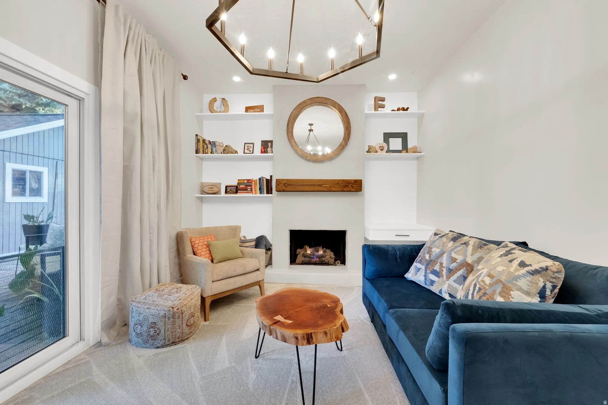 Living area featuring a fireplace with a wood mantle, built-in shelving, and a modern chandelier