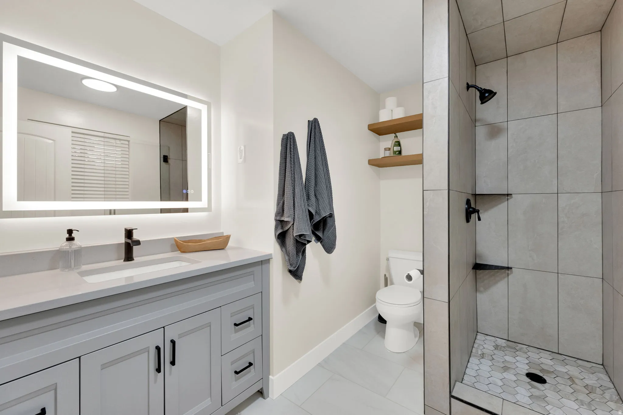 Modern bathroom featuring a single vanity with light grey cabinetry and a light-colored countertop