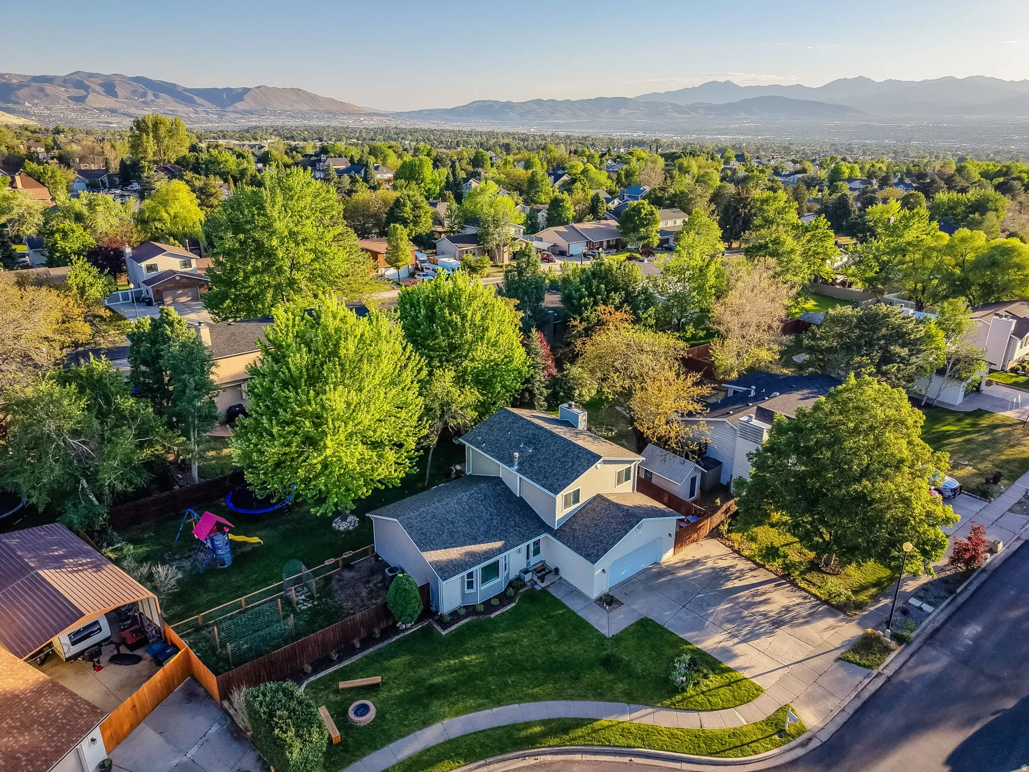 Suburban residence featuring a two-story design with an attached garage, a spacious driveway, and a verdant lawn