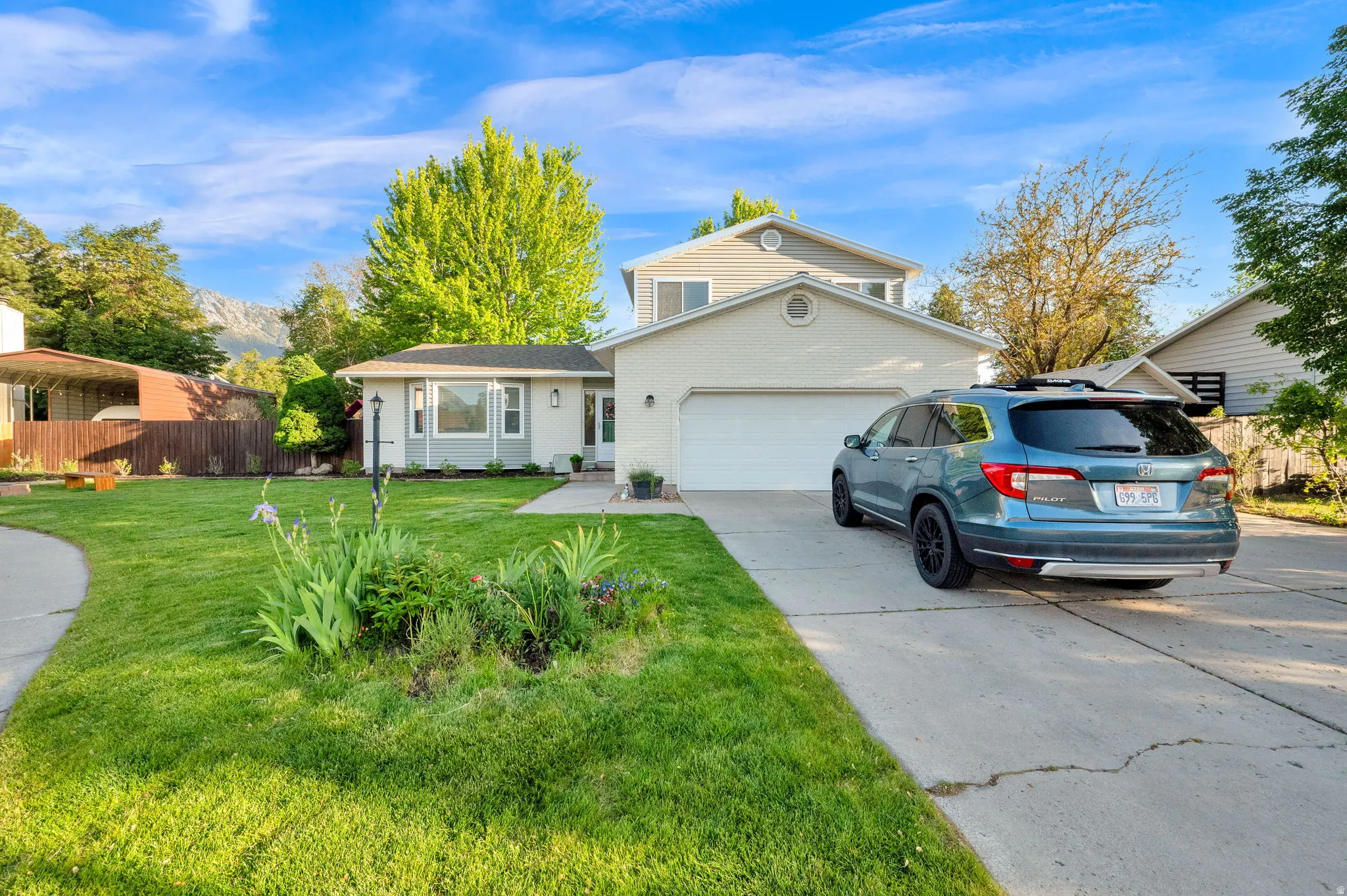 Two-story residence featuring a two-car garage, concrete driveway, and a manicured lawn