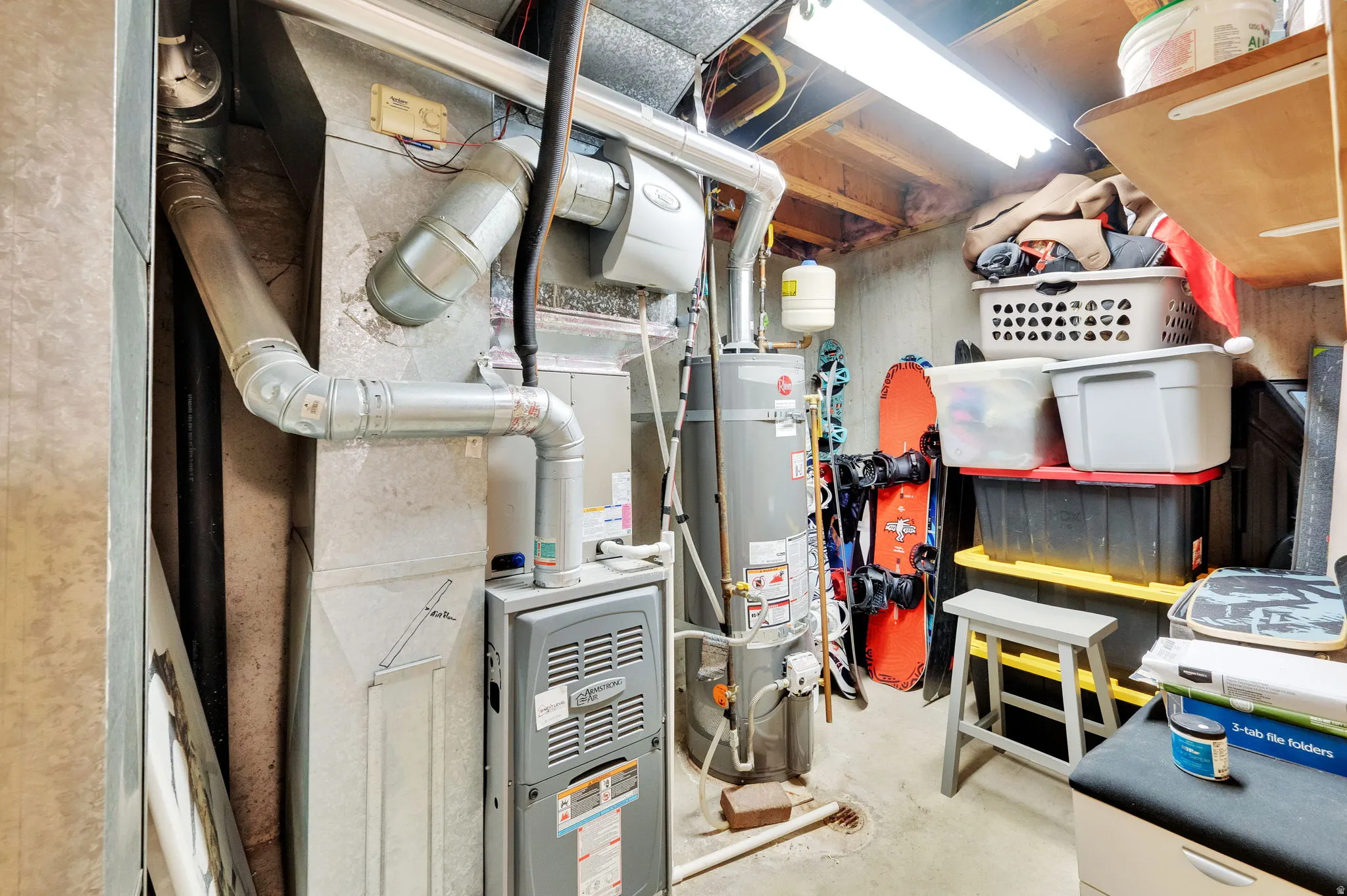 Utility area featuring a water heater and furnace with exposed ductwork, concrete flooring, and ceiling-mounted fluorescent lighting