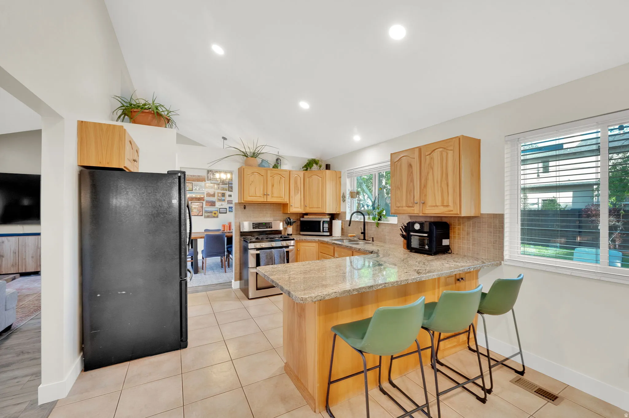 Open-concept kitchen featuring wood cabinetry, stainless steel appliances, and a tiled backsplash