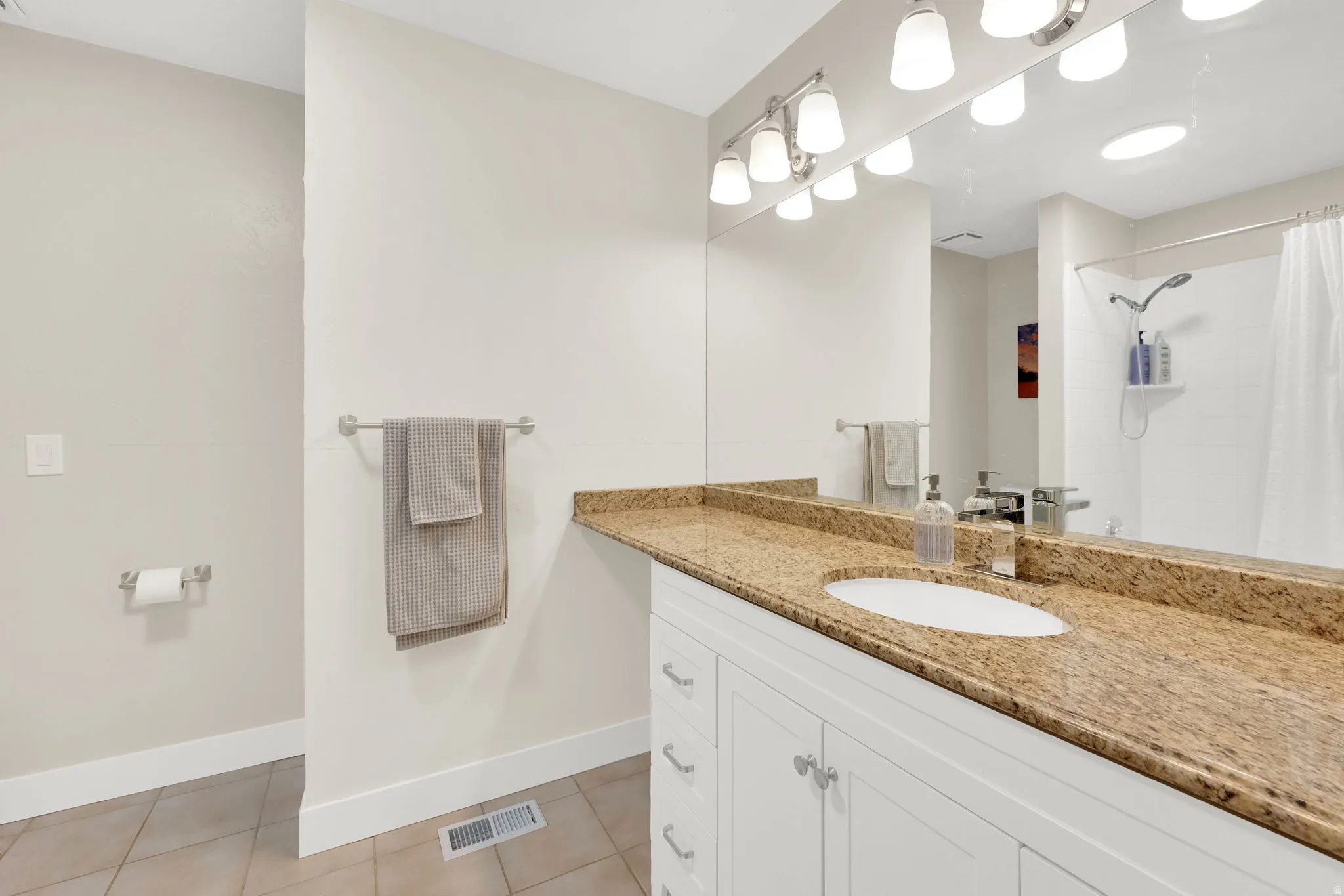 Bathroom featuring a single vanity with an integrated sink, a speckled countertop, and white cabinetry
