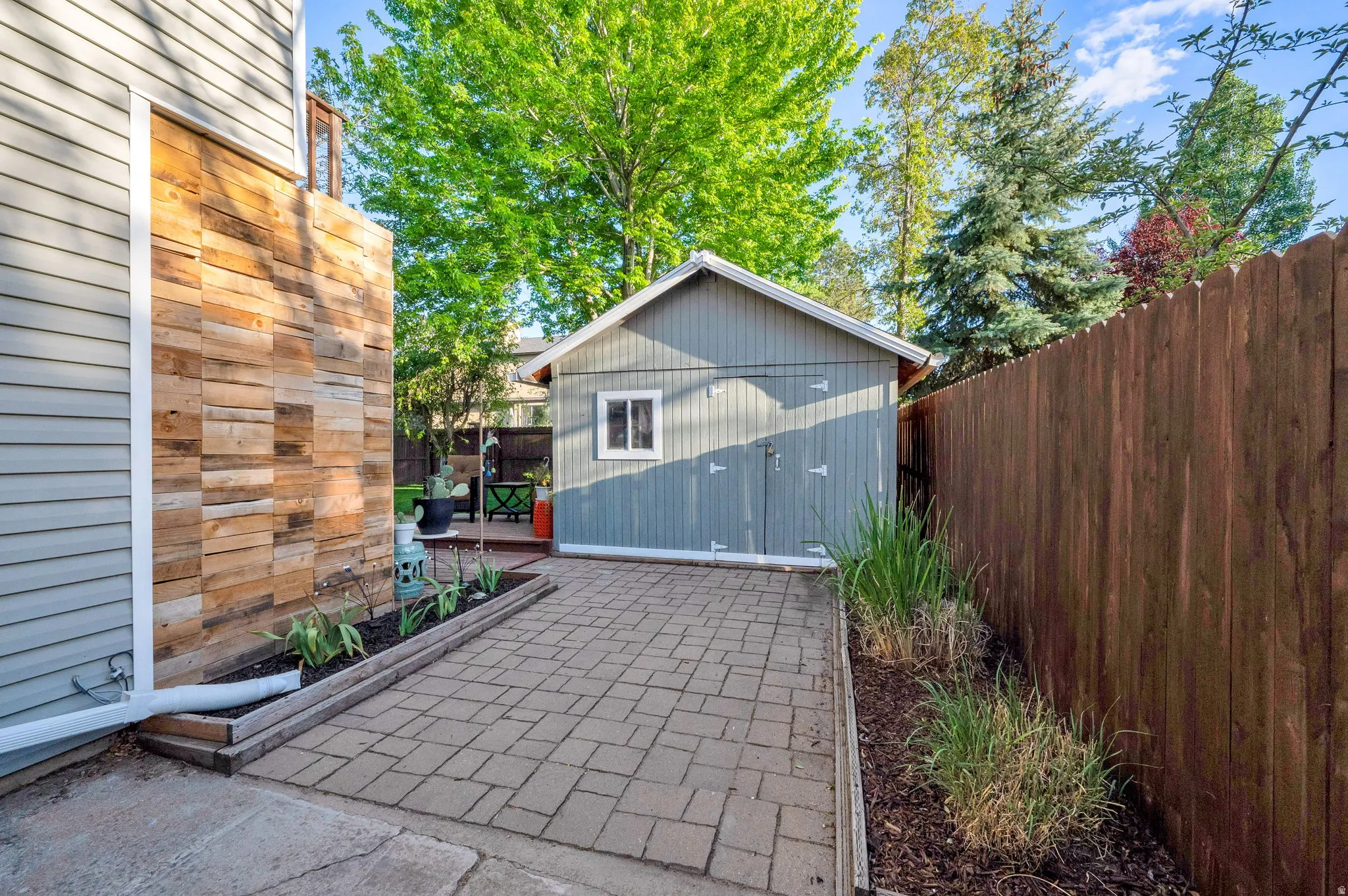 Paved patio area featuring a detached storage shed with double doors and a window