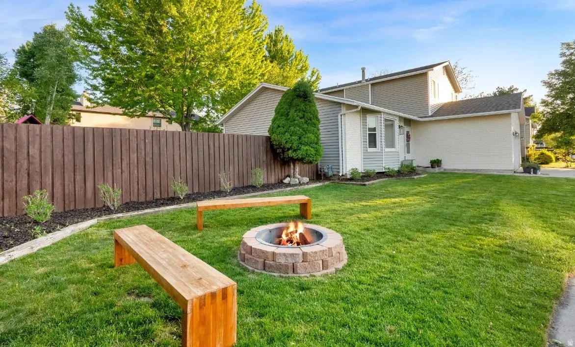 Expansive lawn area featuring a stone fire pit with integrated seating