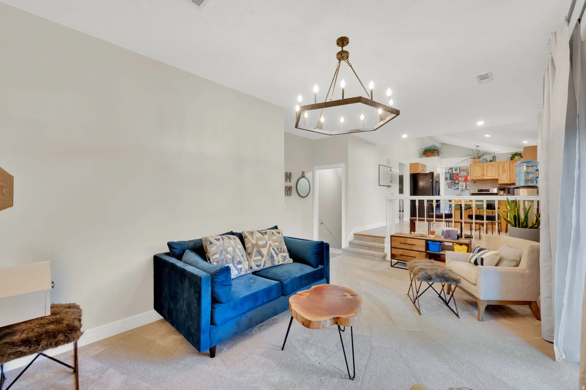 Carpeted living area featuring a vaulted ceiling with an octagonal chandelier