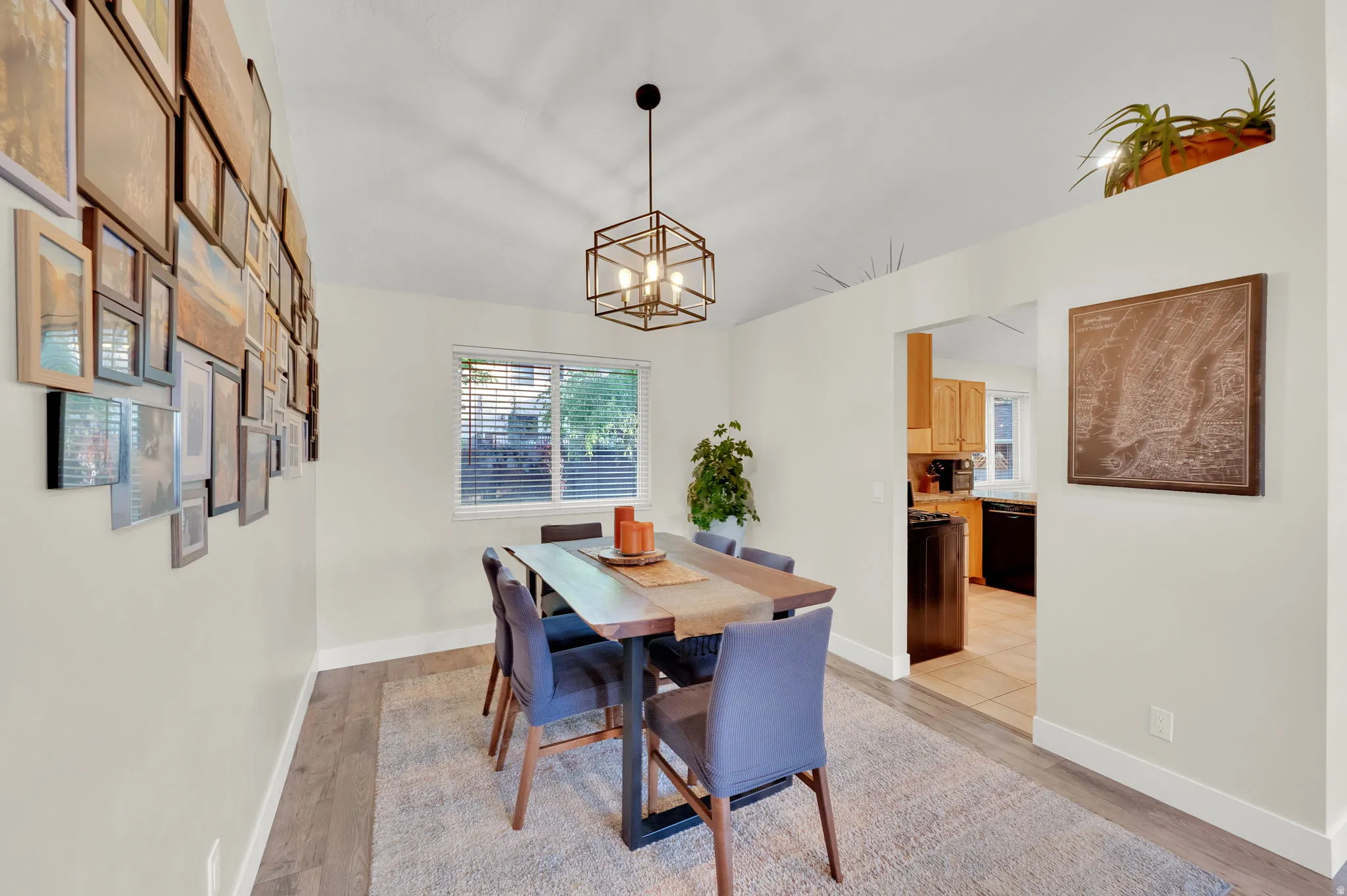 Open-concept dining area featuring wood-finish flooring, a modern geometric chandelier, and white trim
