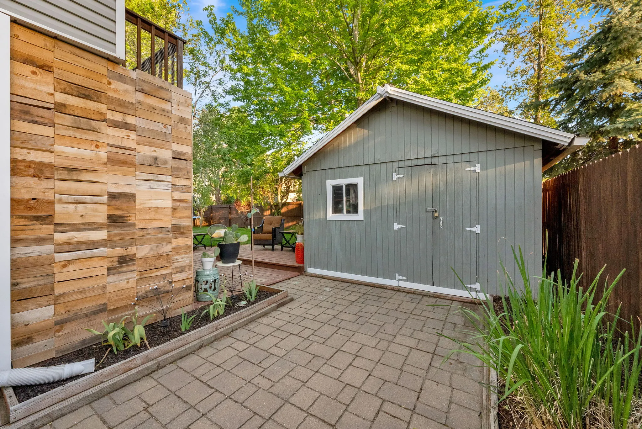 Paved patio area featuring a detached storage shed with a window and double doors