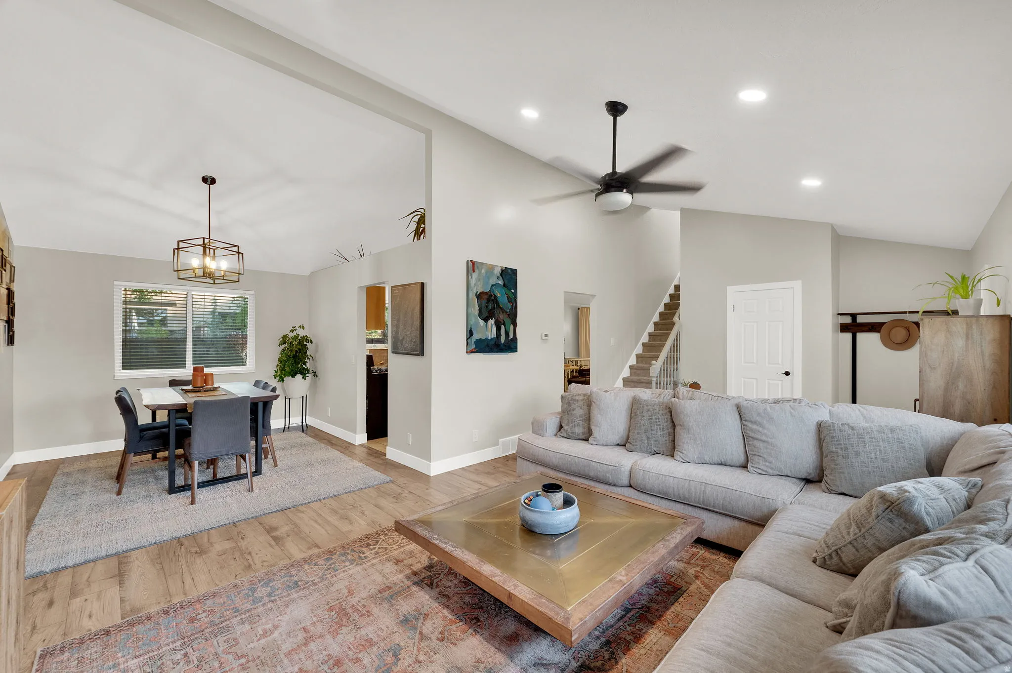 Open-concept living space featuring wood-finish flooring, vaulted ceilings, recessed lighting, and a modern ceiling fan