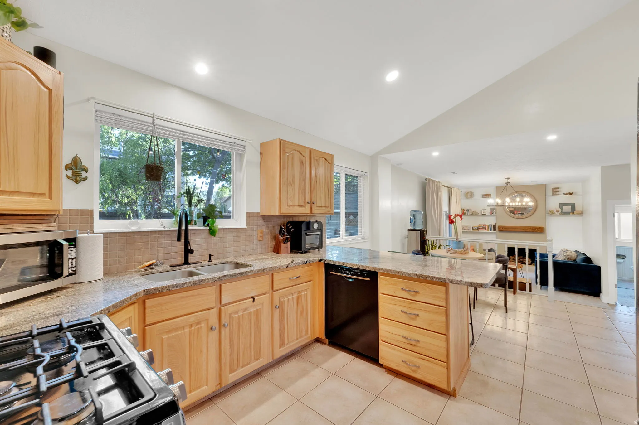 Kitchen featuring wood cabinetry, light-toned countertops, a tile backsplash, and a black built-in dishwasher
