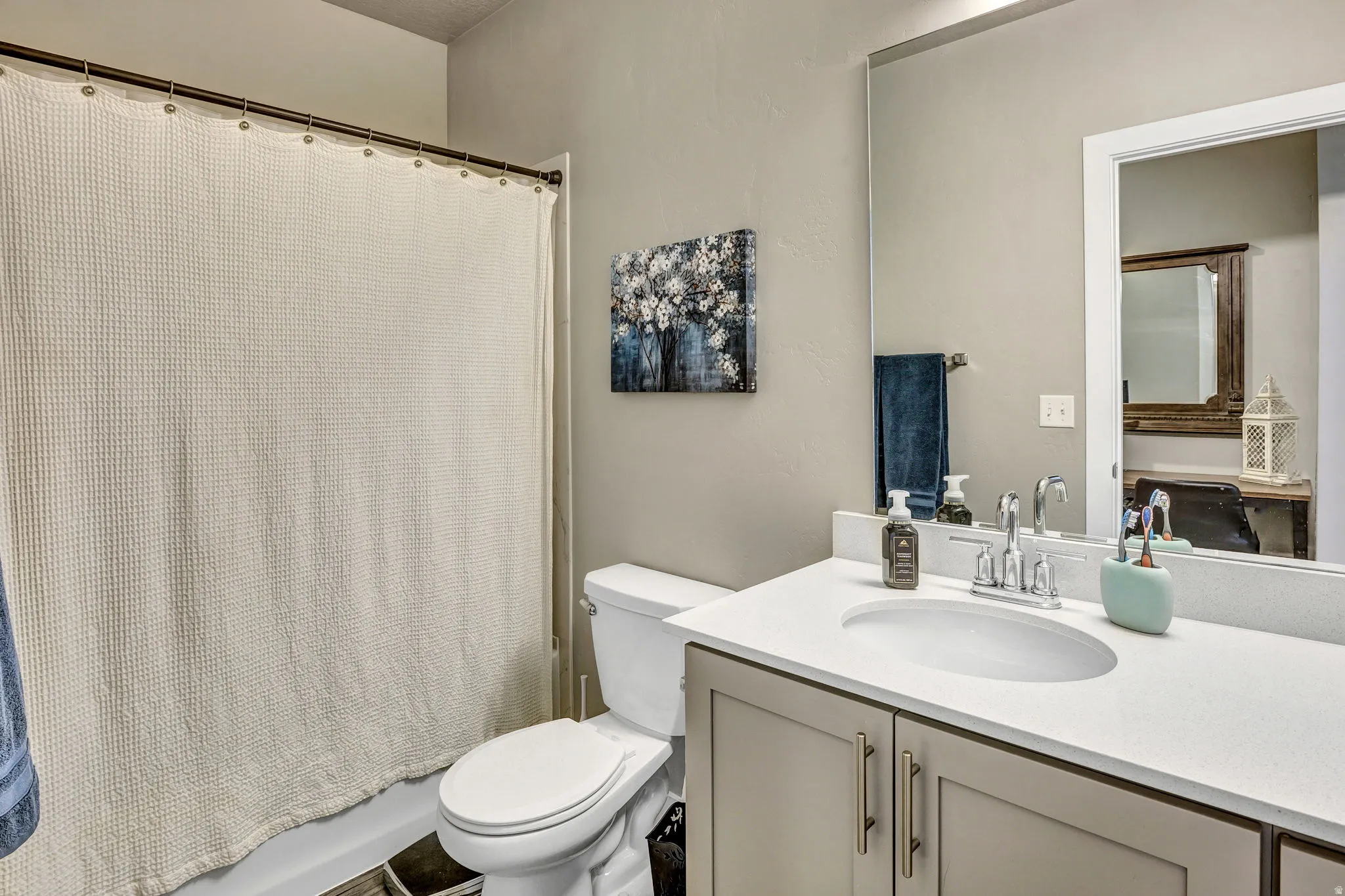 Bathroom with a single vanity featuring a built-in sink, light countertop, and under-sink cabinetry