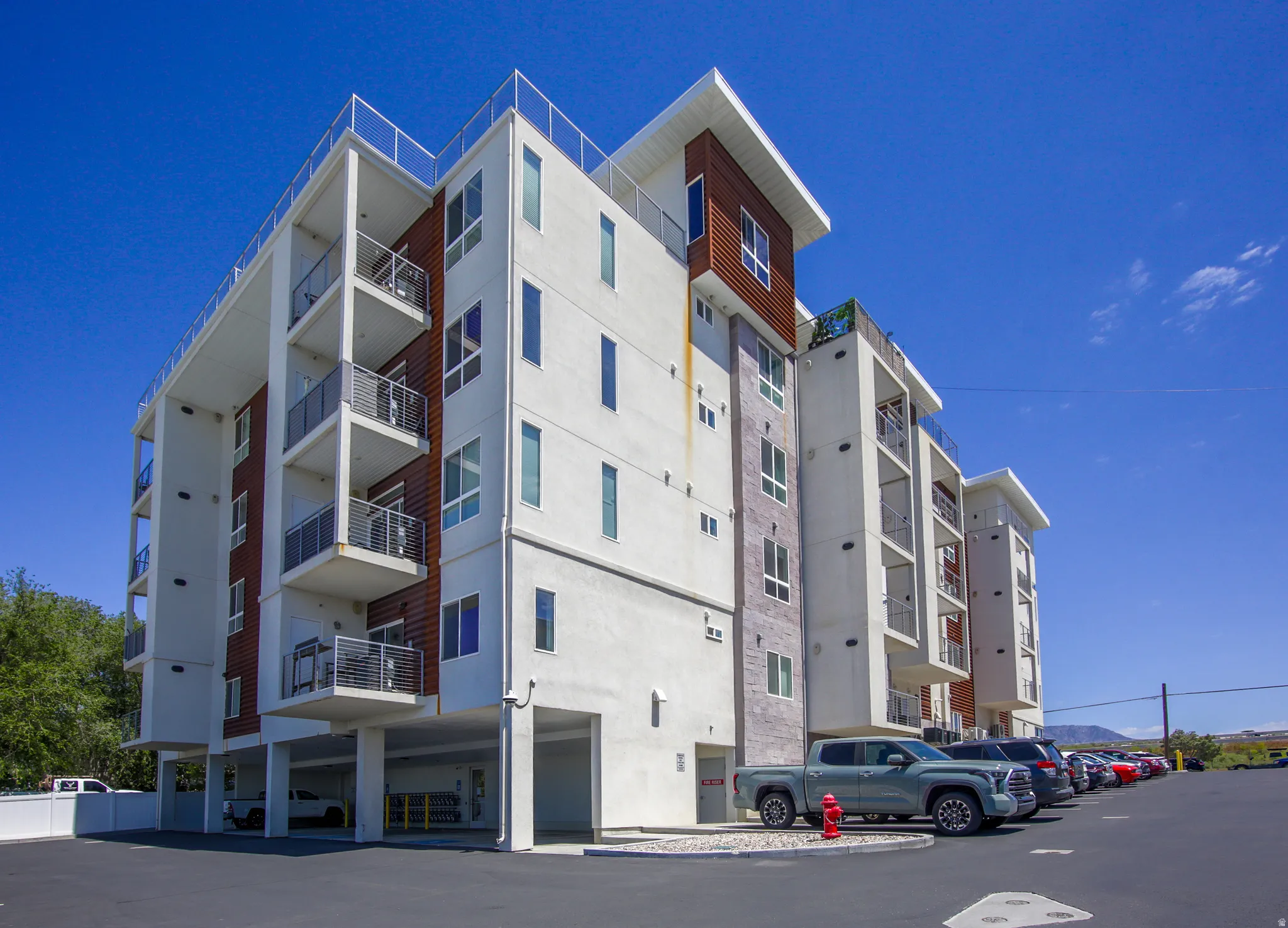 Contemporary multifamily building featuring a white stucco exterior with wood-finish and stone accents