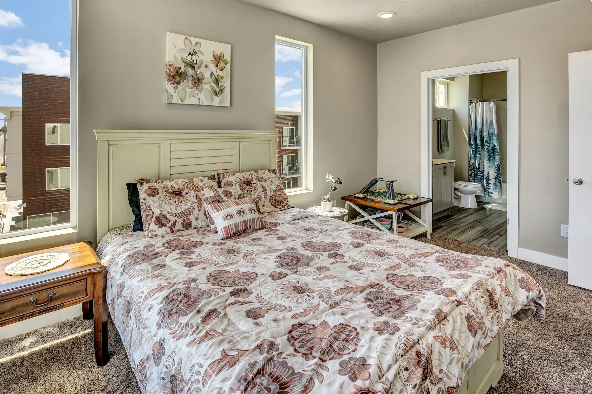 Carpeted bedroom with neutral wall tones and abundant natural light from two tall windows