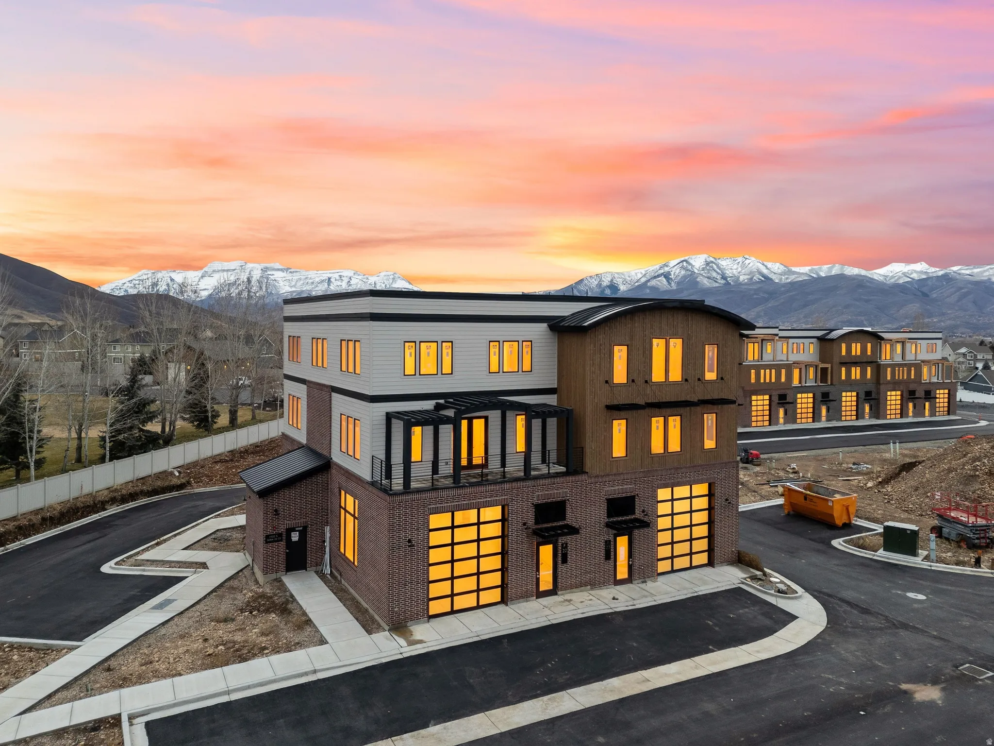 Modern multi-story facade featuring brick and wood-tone siding with contrasting black trim