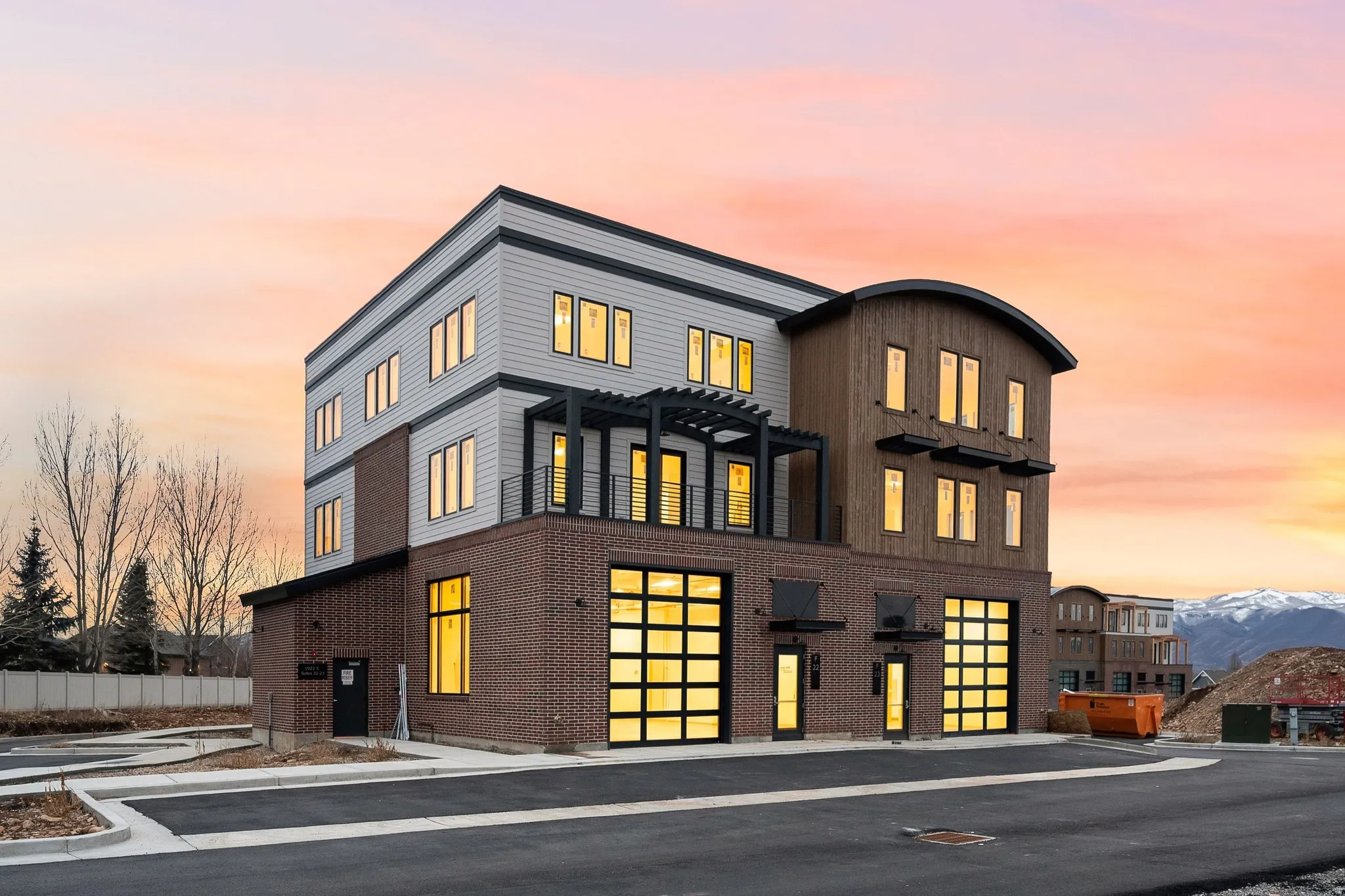 Modern multi-story building featuring a brick base with multiple glass paneled garage doors