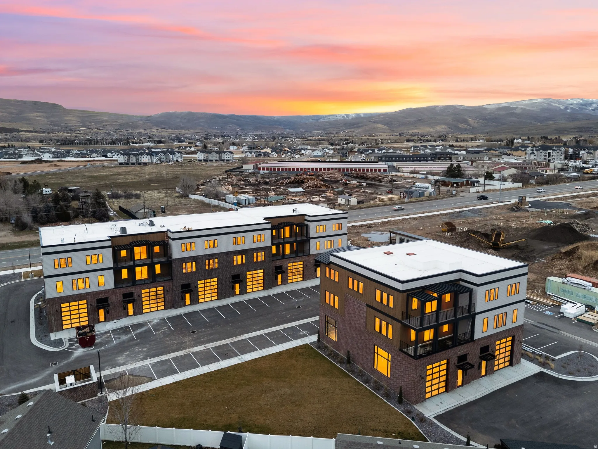 Modern commercial buildings featuring brick and light-toned siding, expansive parking areas, and multiple large garage doors