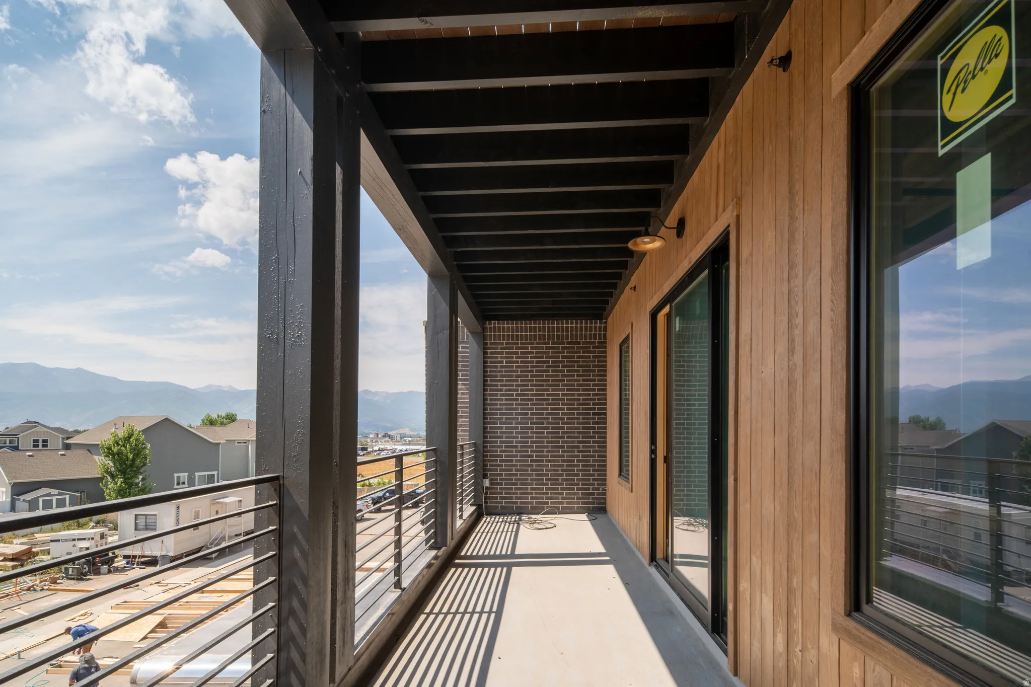 Private balcony featuring a concrete floor, black metal railing, and wood-finish siding