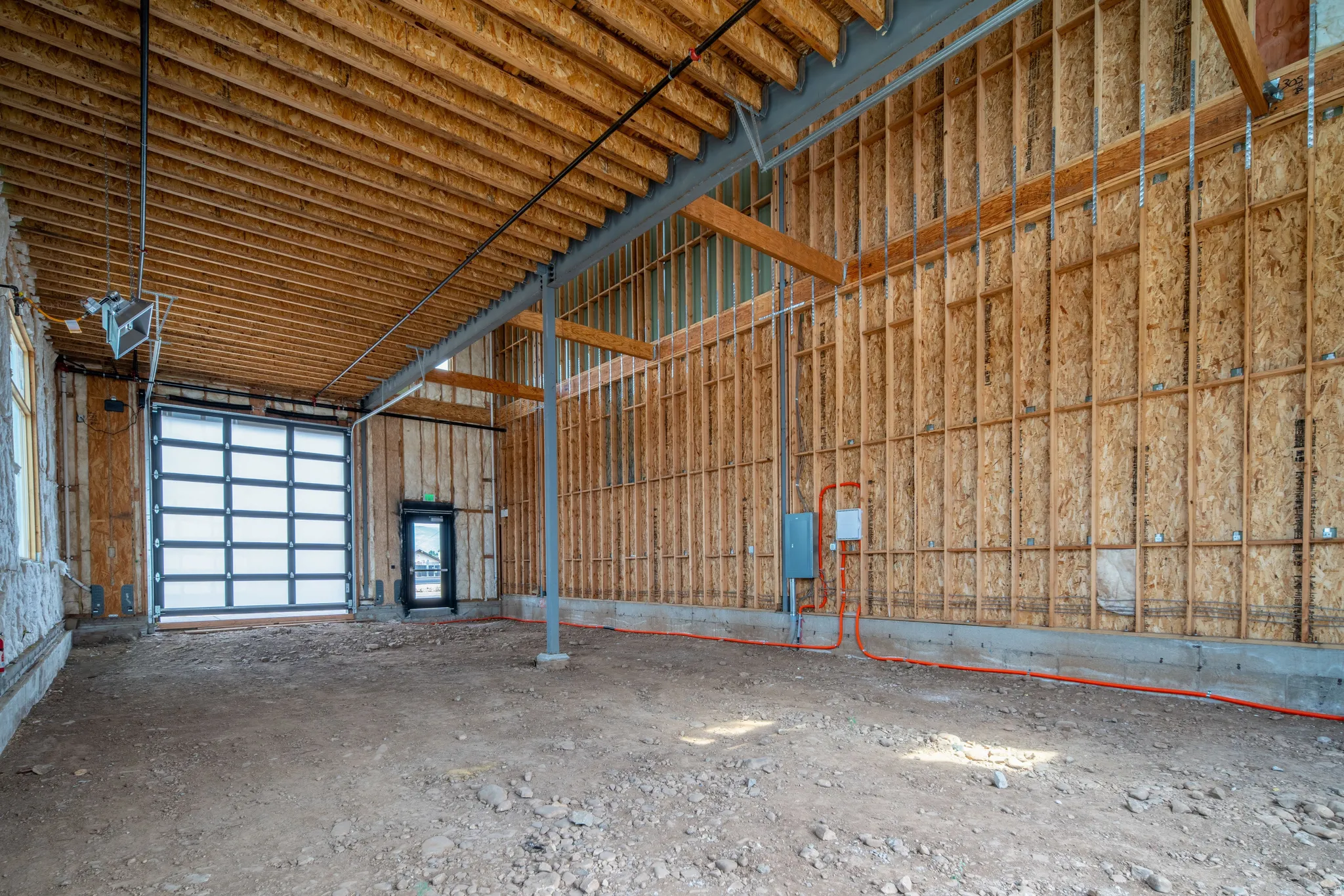 Spacious unfinished interior with a large overhead door and separate entry door