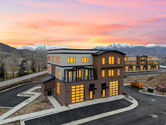 Modern multi-story facade featuring brick and wood-tone siding with contrasting black trim