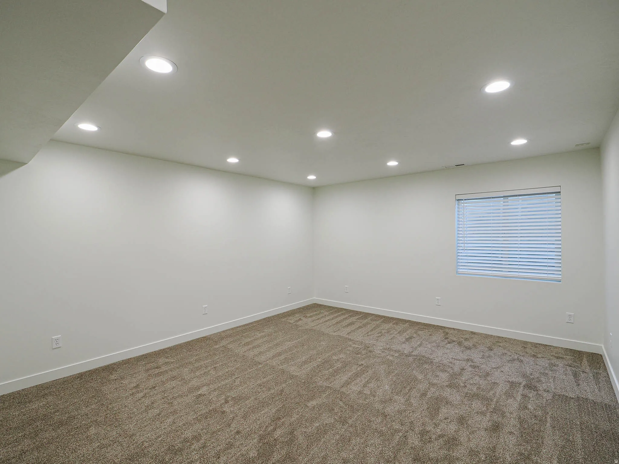 Spacious room featuring neutral paint, recessed lighting, a window with blinds, and carpeted flooring