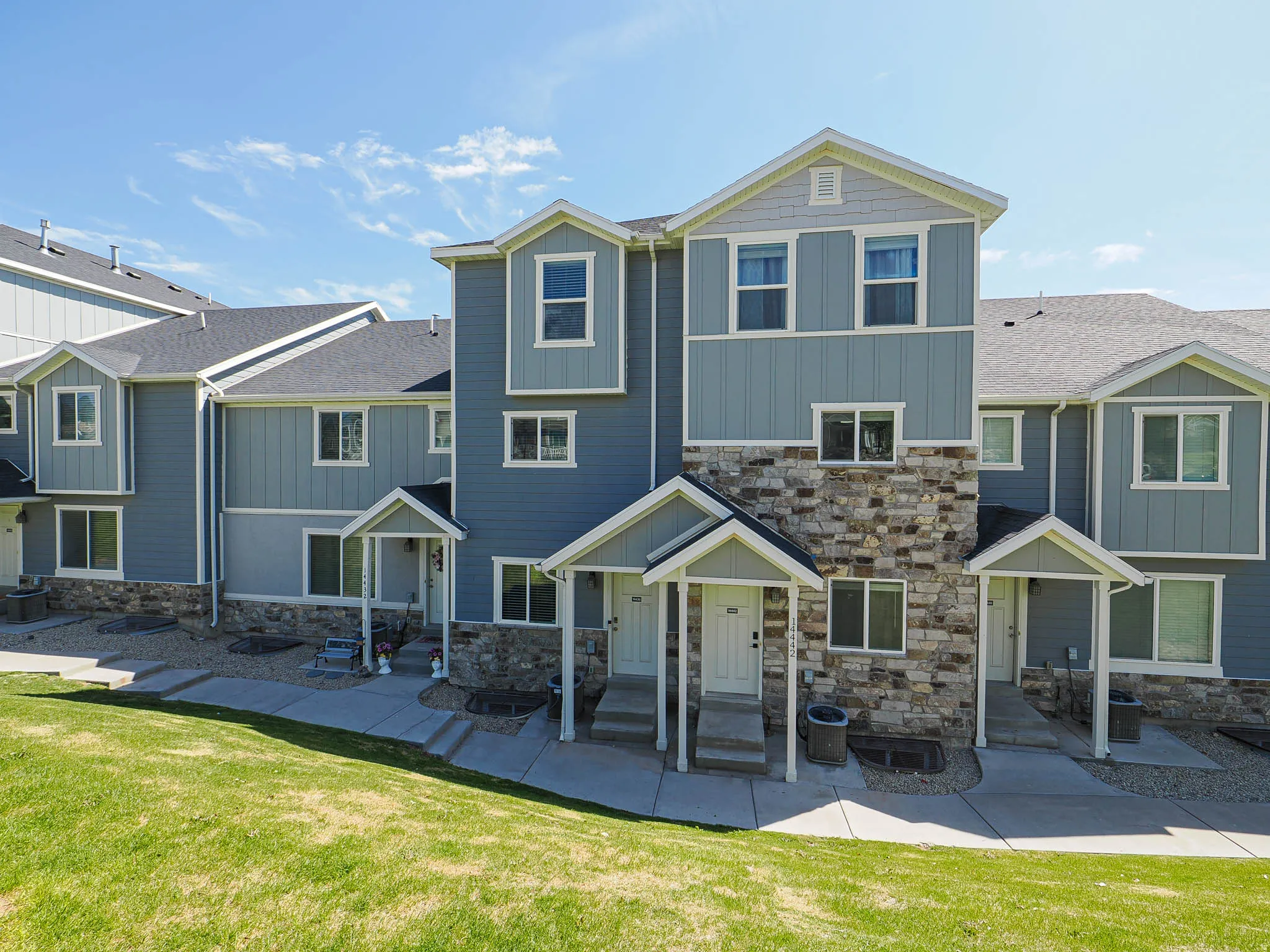 Multi-level townhome featuring blue siding, light gray trim, and stone veneer accents