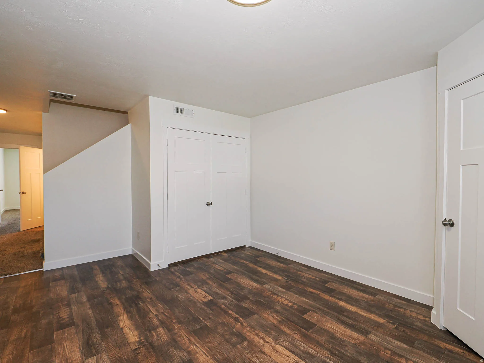 Room featuring wood-finish flooring, crisp white walls, and a recessed ceiling light