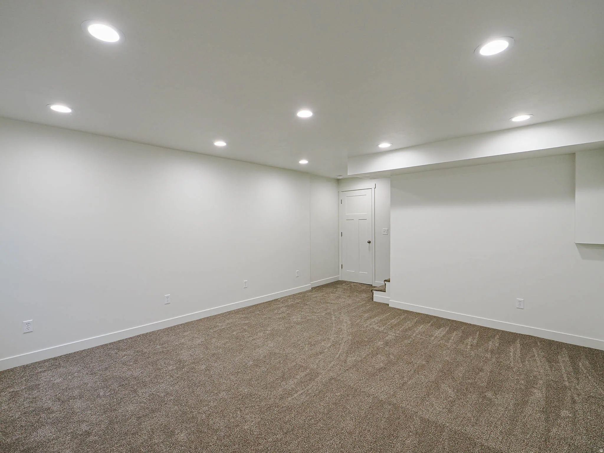 Spacious room featuring neutral carpeting and white walls, complemented by recessed lighting