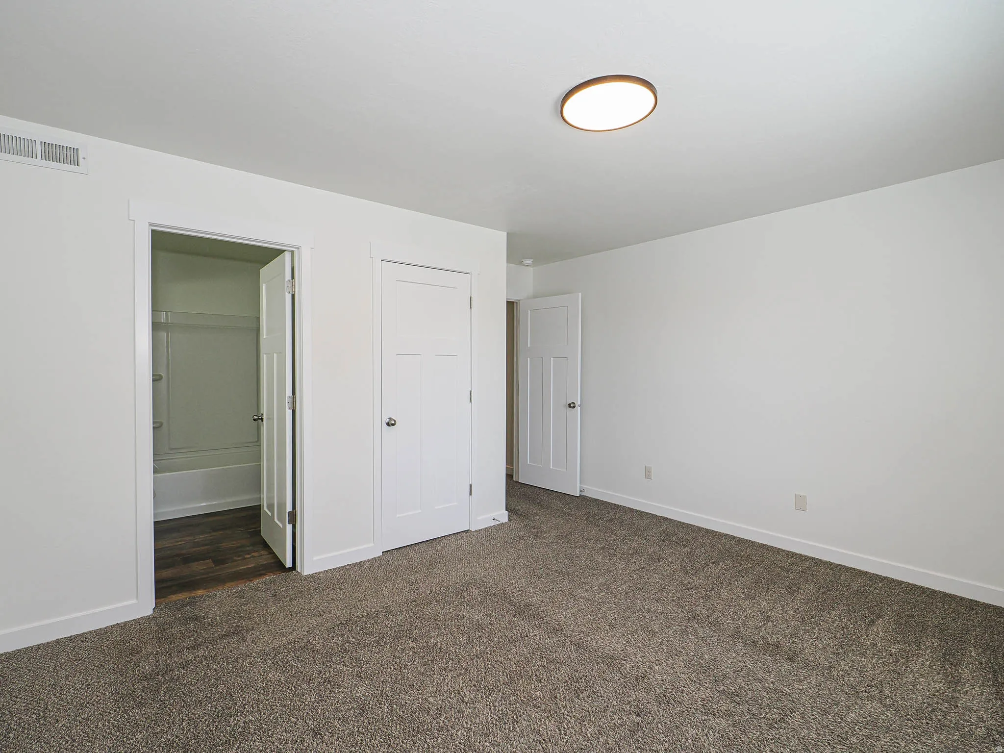 Spacious room featuring neutral carpet flooring and white walls