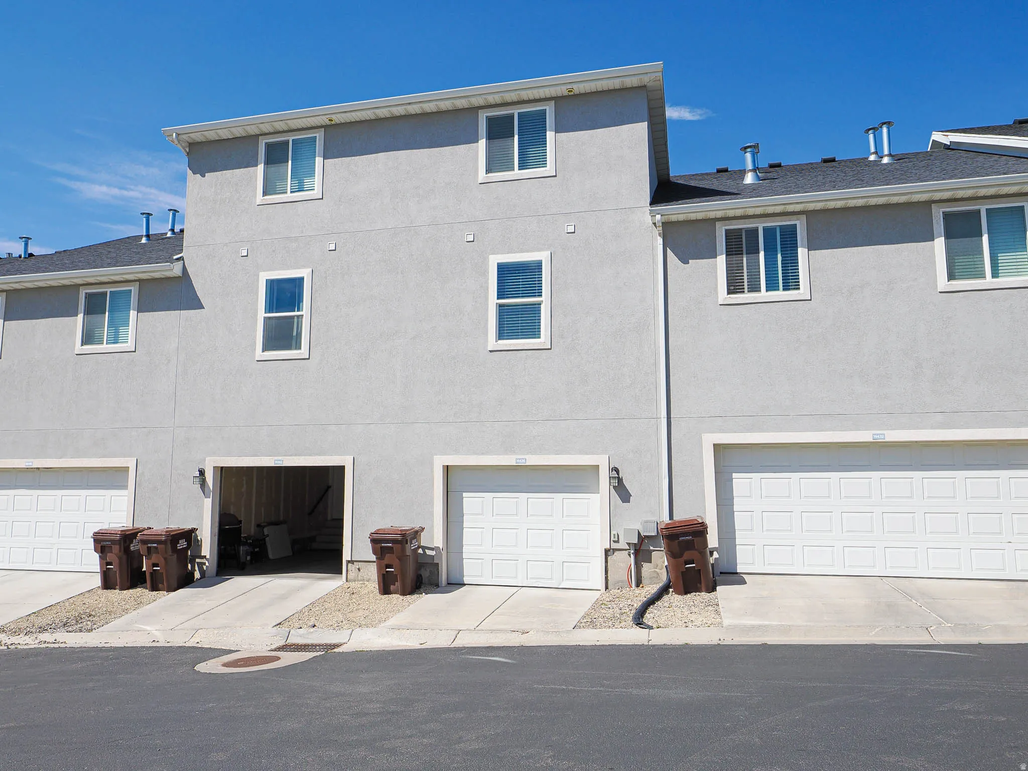 Townhome exterior with light gray stucco finish and white trim windows