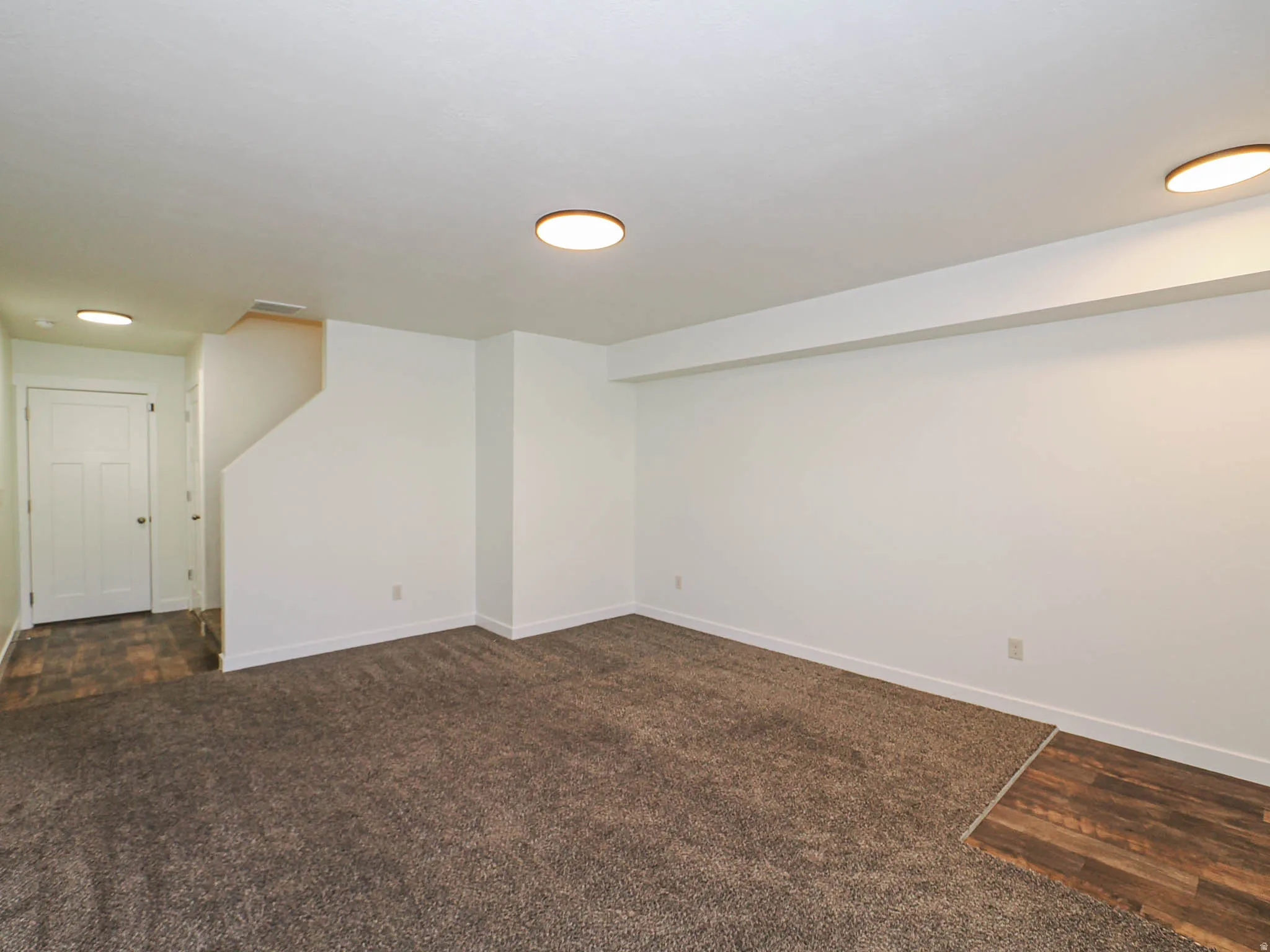 Spacious room featuring plush carpeting, crisp white walls, and recessed lighting
