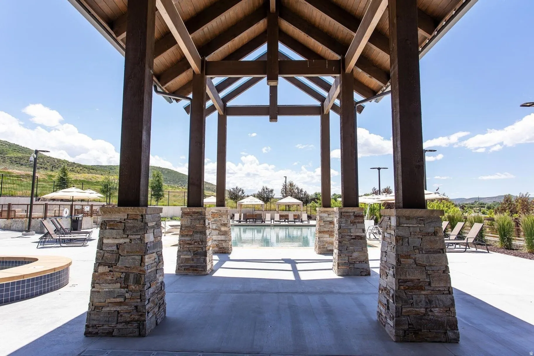 Open-air pavilion featuring exposed wood beams and stone-clad pillars