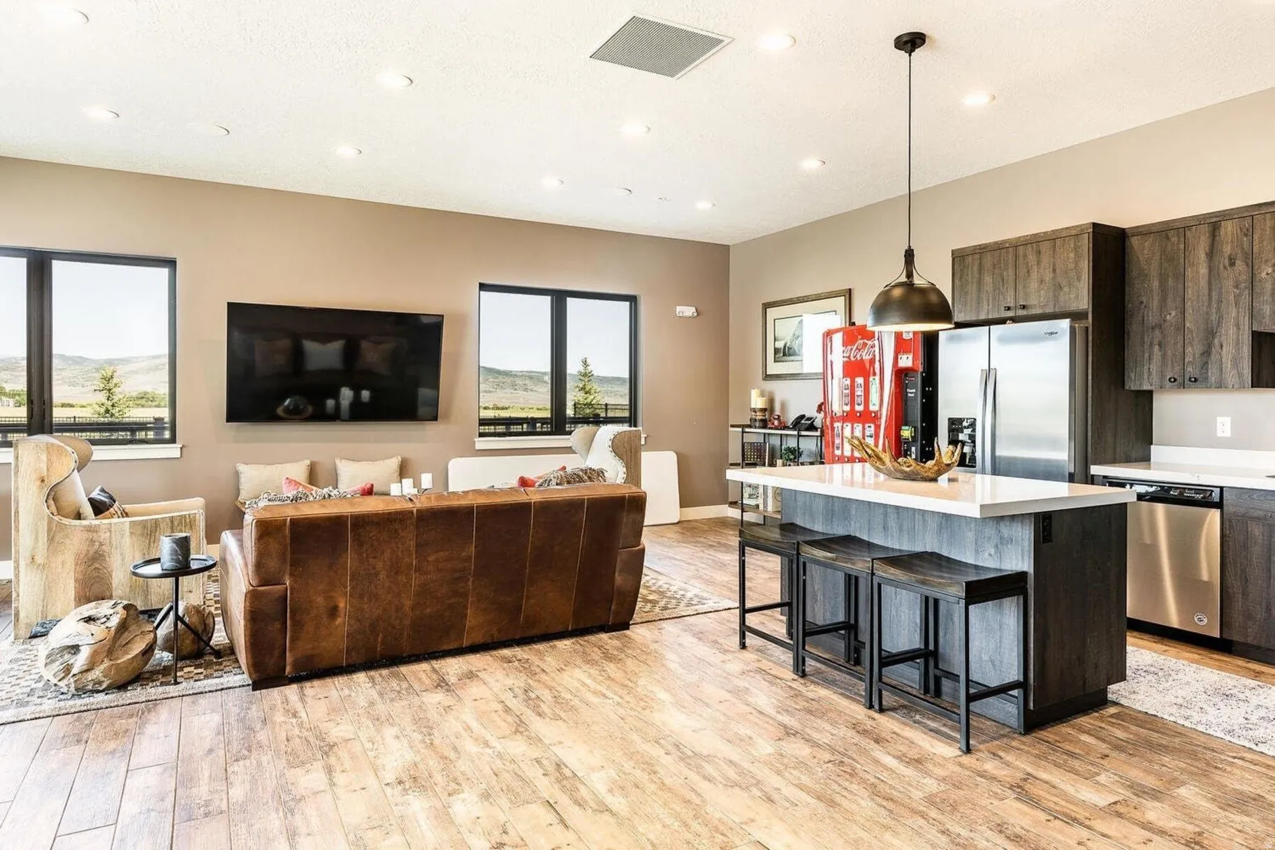 Open-concept living space featuring wood-finish flooring, recessed lighting, and large windows with outdoor scenery