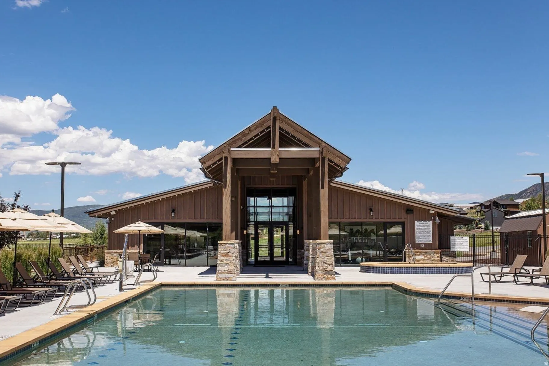 Outdoor swimming pool with integrated hot tub, surrounded by a concrete deck