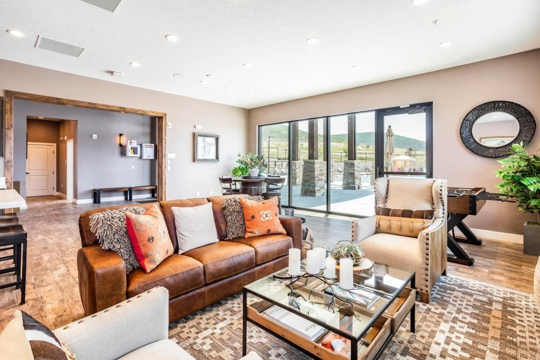 Spacious open-concept living area featuring wood-finish flooring, recessed lighting, and a large glass door system opening to an outdoor patio with stone columns