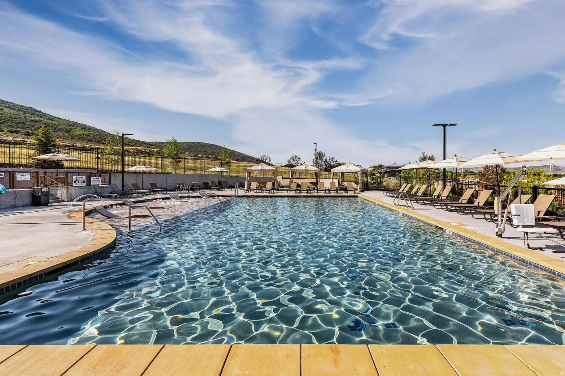 Rectangular swimming pool featuring a curved entry, concrete decking, and integrated handrails